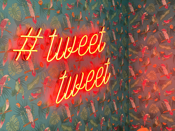 Industrial background with neon sign reading #tweet tweet